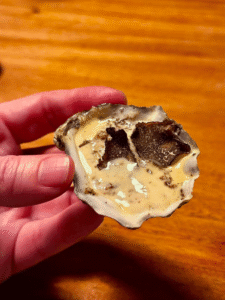 A customer holding one of the baked oysters with truffle cream sauce in his hand